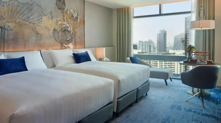 a hotel room with two beds and a large window at Chatrium Grand Bangkok in Bangkok