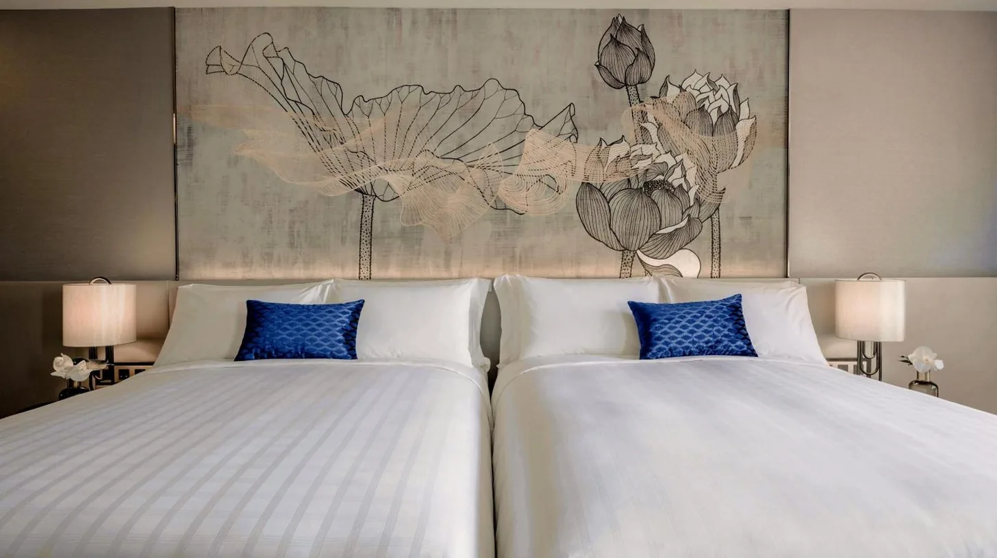 two beds with blue pillows in a hotel room at Chatrium Grand Bangkok in Bangkok
