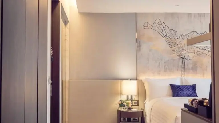 a bedroom with a bed with a painting on the wall at Chatrium Grand Bangkok in Bangkok