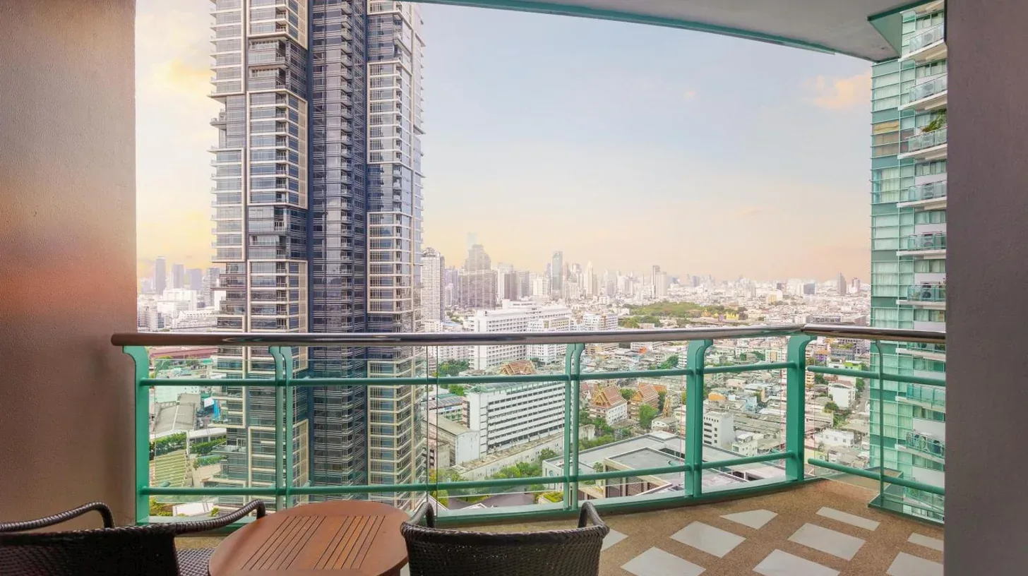 a balcony with chairs and a view of a city at Chatrium Hotel Riverside Bangkok in Bangkok