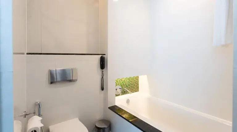 a hotel room with two beds and a desk and a window at Chatrium Hotel Riverside Bangkok in Bangkok