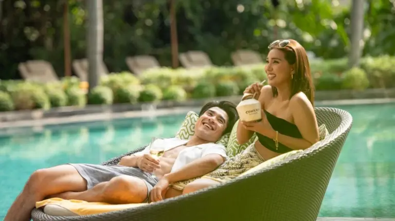 dos personas sentadas en sillas de jardín junto a una piscina en Conrad Bangkok en Bangkok
