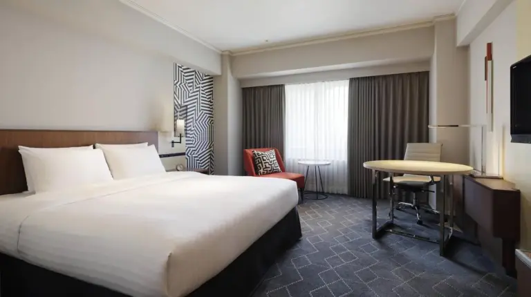 a hotel room with a large bed and a table at Courtyard by Marriott Shin-Osaka Station in Osaka