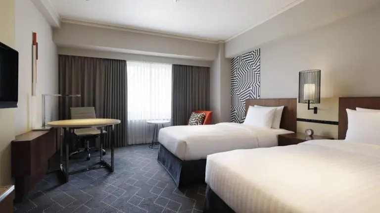 a hotel room with two beds and a table at Courtyard by Marriott Shin-Osaka Station in Osaka