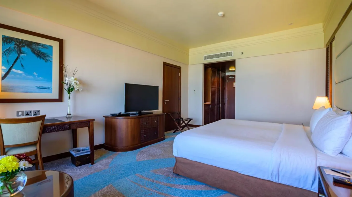 a hotel room with a bed and a desk and a television at Danat Jebel Dhanna Resort in Jebel Dhanna