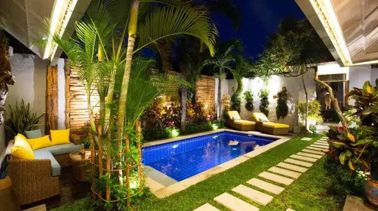 a backyard with a swimming pool and palm trees at Delight ART Villas in Seminyak