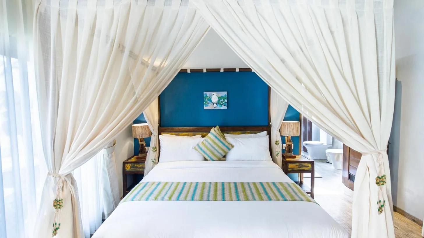 a bedroom with a canopy bed with white curtains at Delight ART Villas in Seminyak