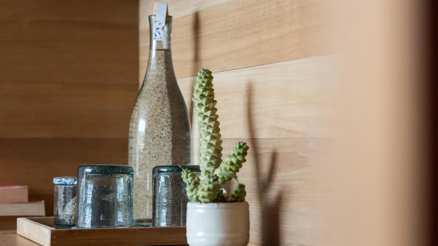 a cactus and glasses on a table with a bottle at Desa Potato Head Bali in Seminyak