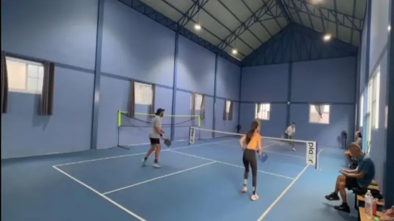 two people playing tennis on a tennis court at Downtown Oasis 芭提雅市中心独栋泳池别墅 A 5卧6卫 KTV BBQ 芭提雅海滩步行街500m in Pattaya South