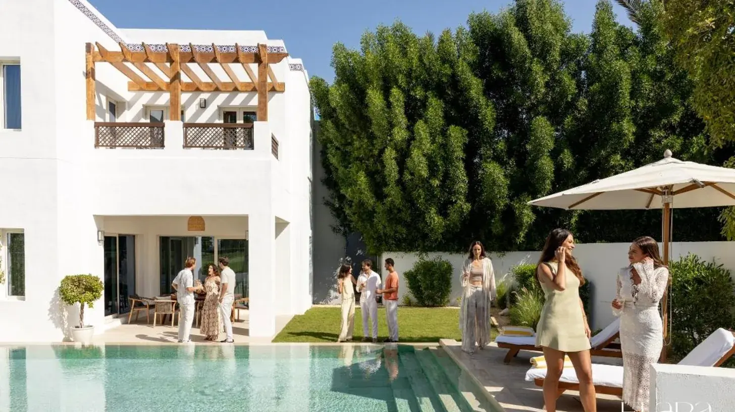 a group of people standing around a swimming pool at Elara & Golf Villas - curated by Park Hyatt Dubai in Dubai