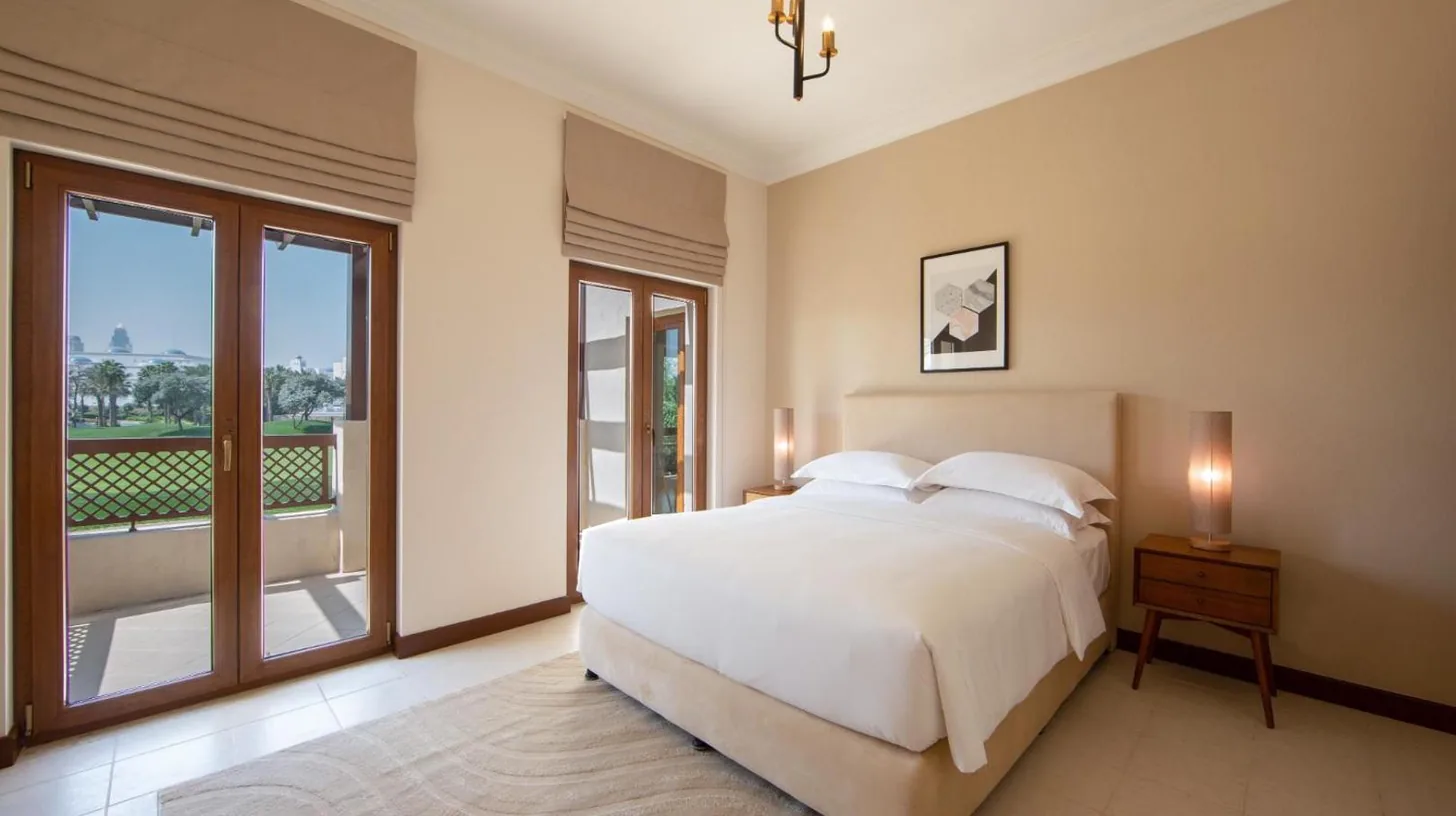 a bedroom with a large white bed and a balcony at Elara & Golf Villas - curated by Park Hyatt Dubai in Dubai