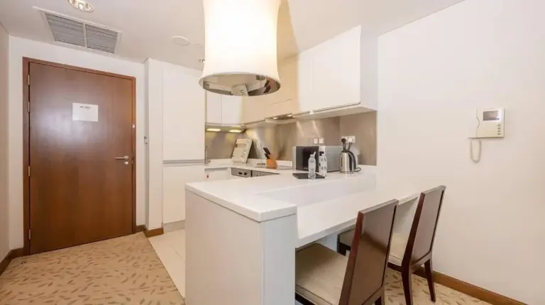 a kitchen with a white counter and a table and chairs at Emaar Fashion Avenue - Formerly Address Dubai Mall Four Apple in Dubai