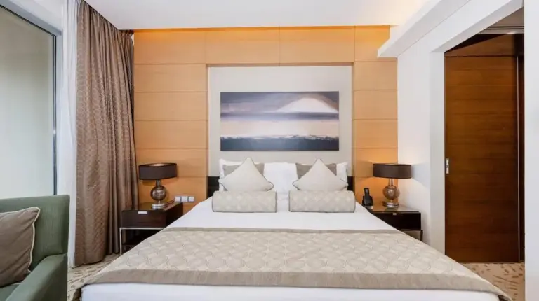 a bedroom with a large bed with two tables and two lamps at Emaar Fashion Avenue - Formerly Address Dubai Mall Four Apple in Dubai