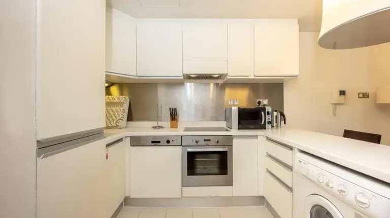 a kitchen with white cabinets and a microwave at Emaar Fashion Avenue - Formerly Address Dubai Mall Four Apple in Dubai