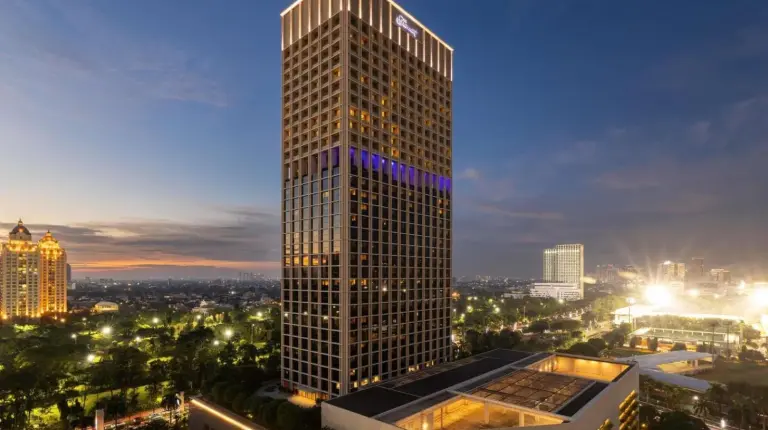a tall building with lights on it in a city at Fairmont Jakarta in Jakarta