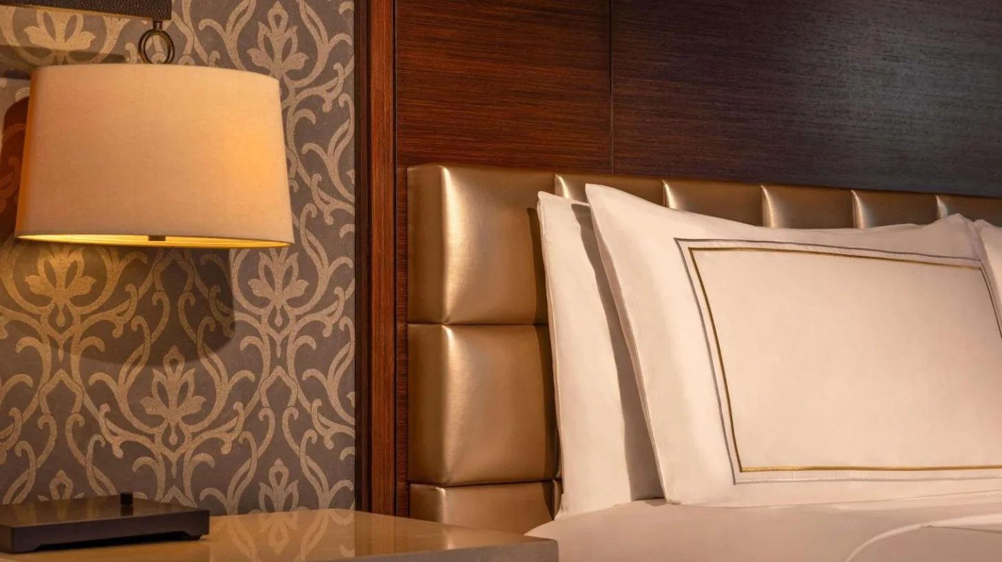 a bedroom with a bed and a table with a lamp at Fairmont Jakarta in Jakarta