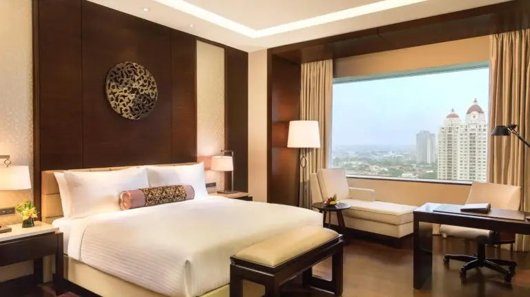 a bedroom with a bed and a desk and a computer at Fairmont Jakarta in Jakarta