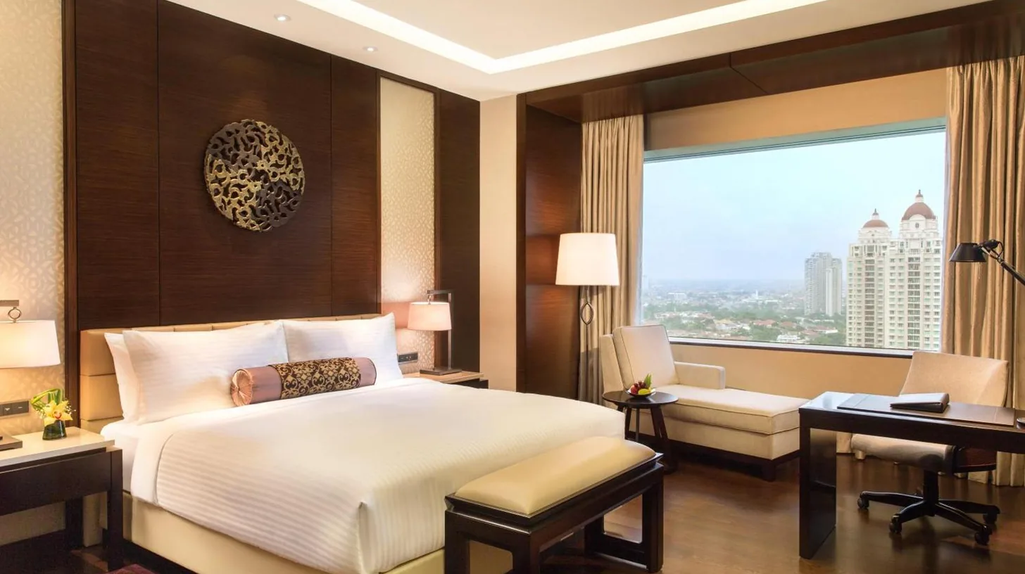 a bedroom with a bed and a desk and a computer at Fairmont Jakarta in Jakarta