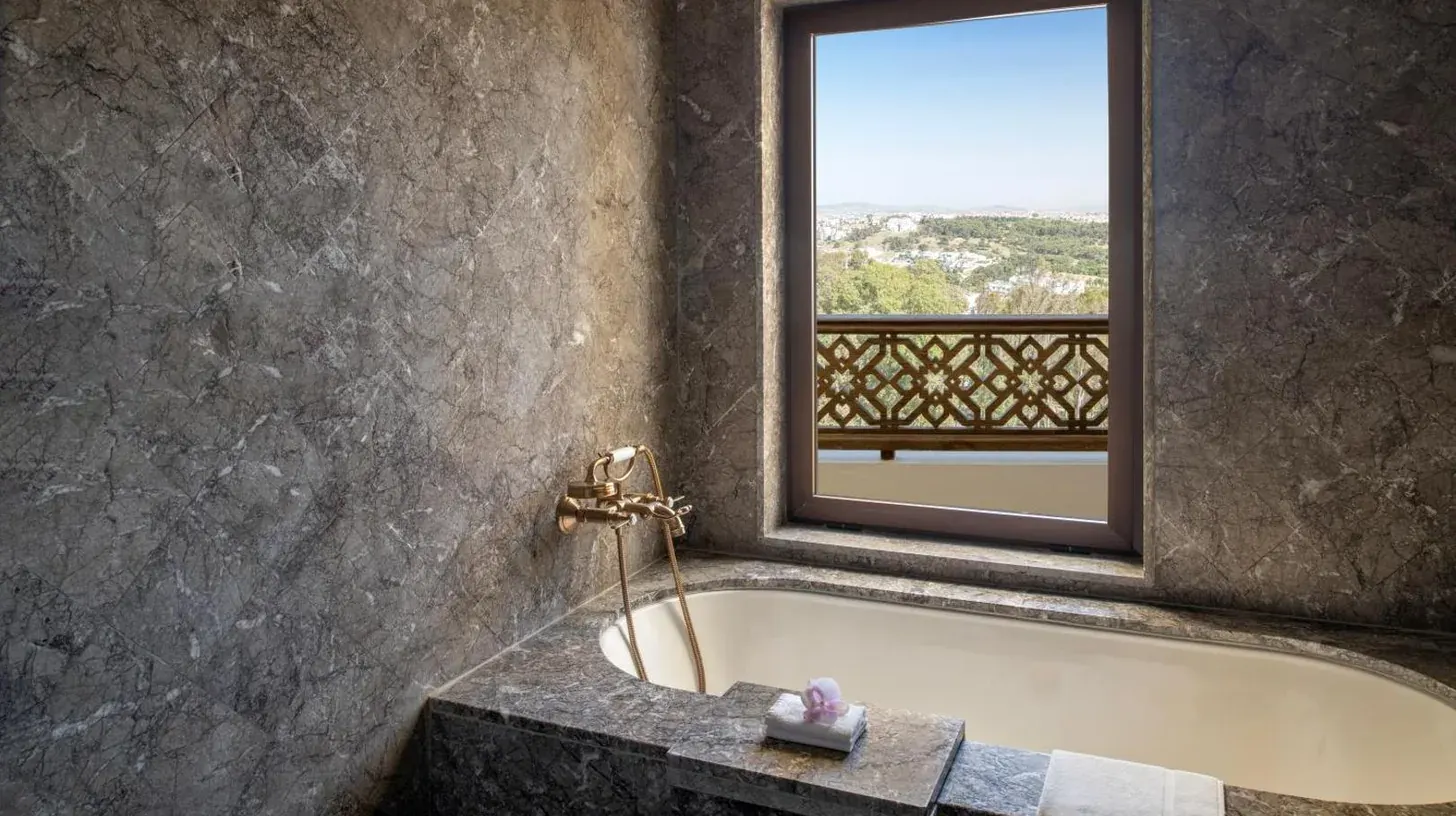 a bathroom with a bath tub with a window at Fairmont Tazi Palace Tangier in Tangier