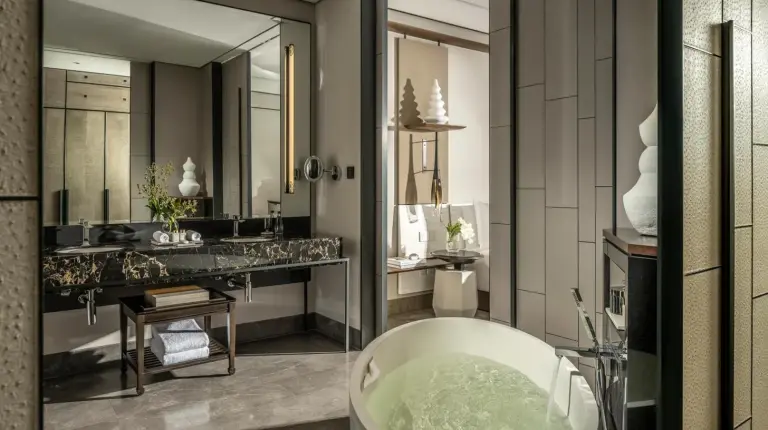 un baño con una bañera y un gran espejo en Four Seasons Hotel Bangkok at Chao Phraya River en Bangkok