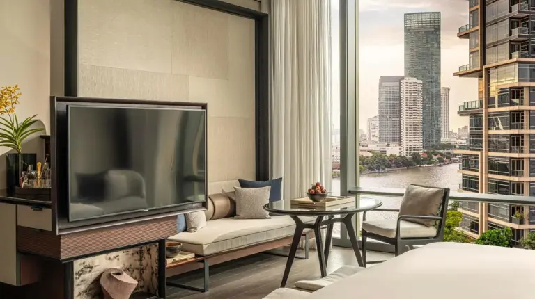una sala de estar con un televisor y una gran ventana en Four Seasons Hotel Bangkok at Chao Phraya River en Bangkok