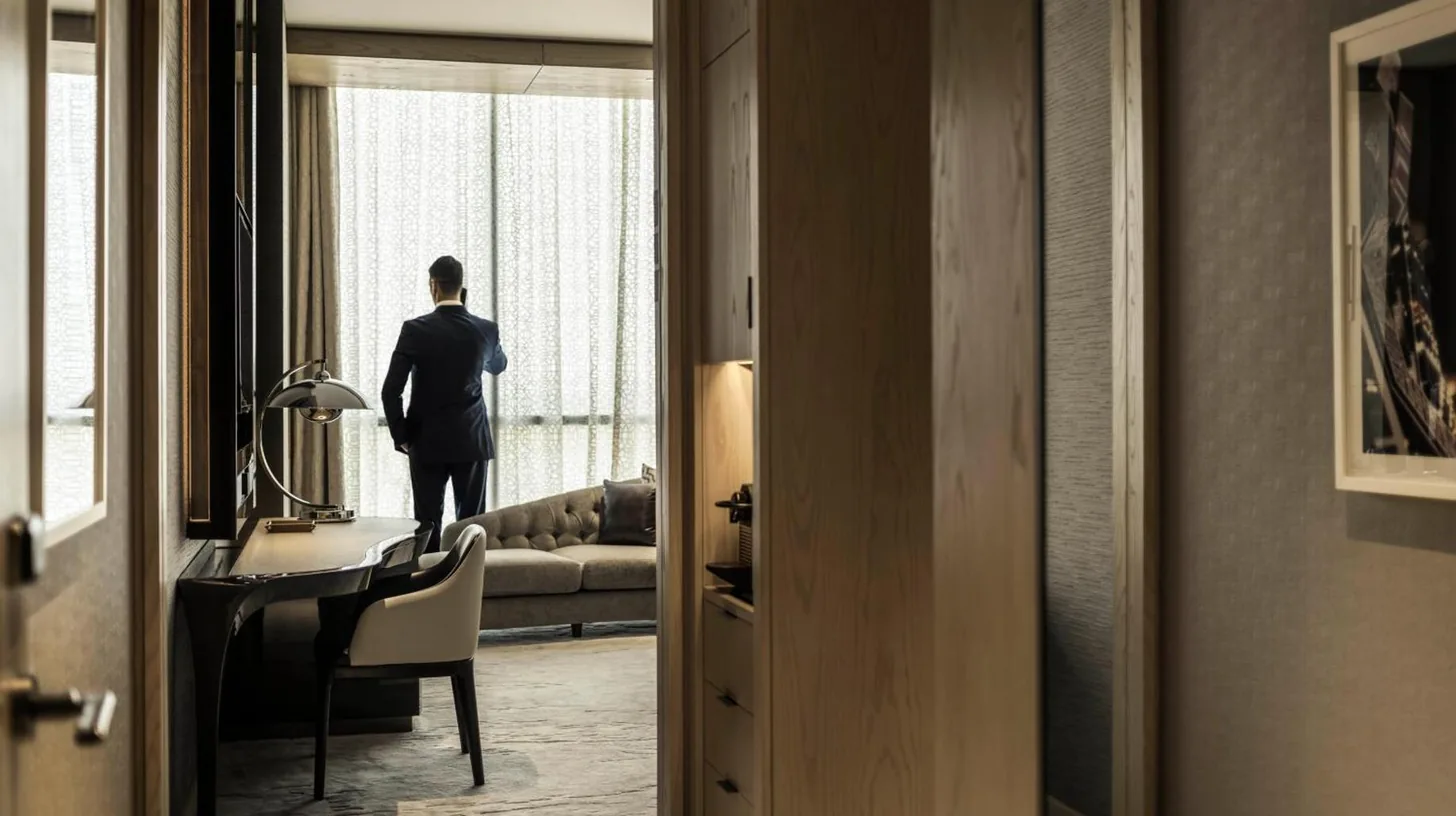 un hombre con traje mirando por la ventana en Four Seasons Hotel Dubai International Financial Centre en Dubái