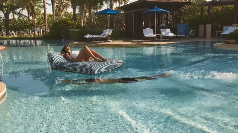 a woman laying on a chair in a swimming pool at Four Seasons Resort Dubai at Jumeirah Beach in Dubai