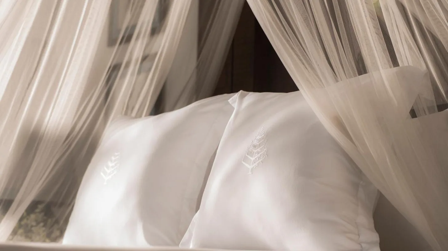 a white bed with white curtains and pillows at Four Seasons Resort Koh Samui in Mae Nam