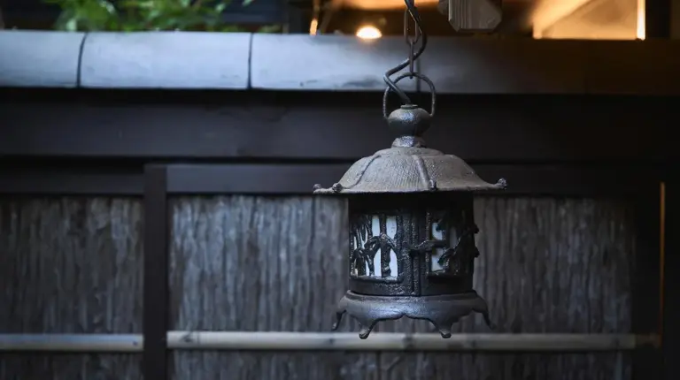 an old lantern hanging over a wooden fence at Futaai Kyoto Machiya Private Villa in Kyoto