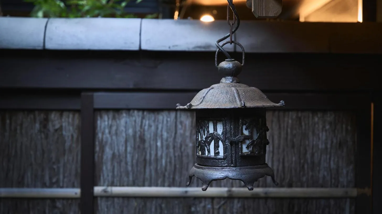 an old lantern hanging over a wooden fence at Futaai Kyoto Machiya Private Villa in Kyoto