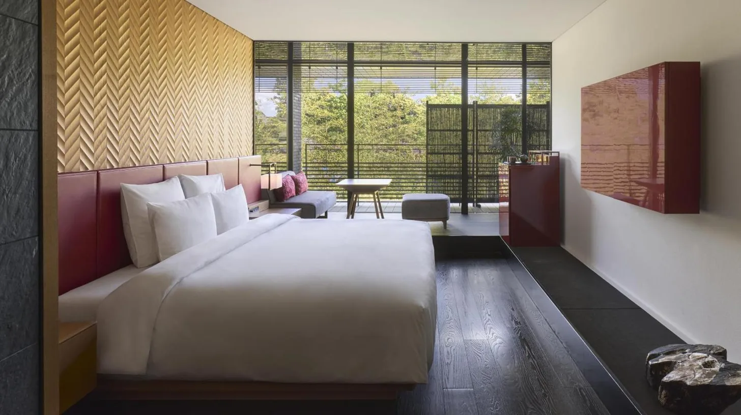 a bedroom with a large bed and a table at Garrya Nijo Castle Kyoto in Kyoto
