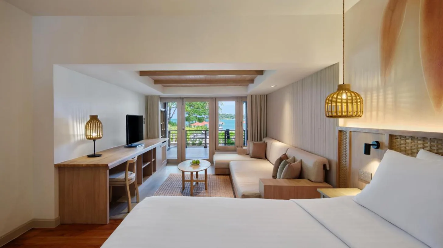 a hotel room with a bed and a living room at Garrya Tongsai Bay Samui in Choeng Mon Beach