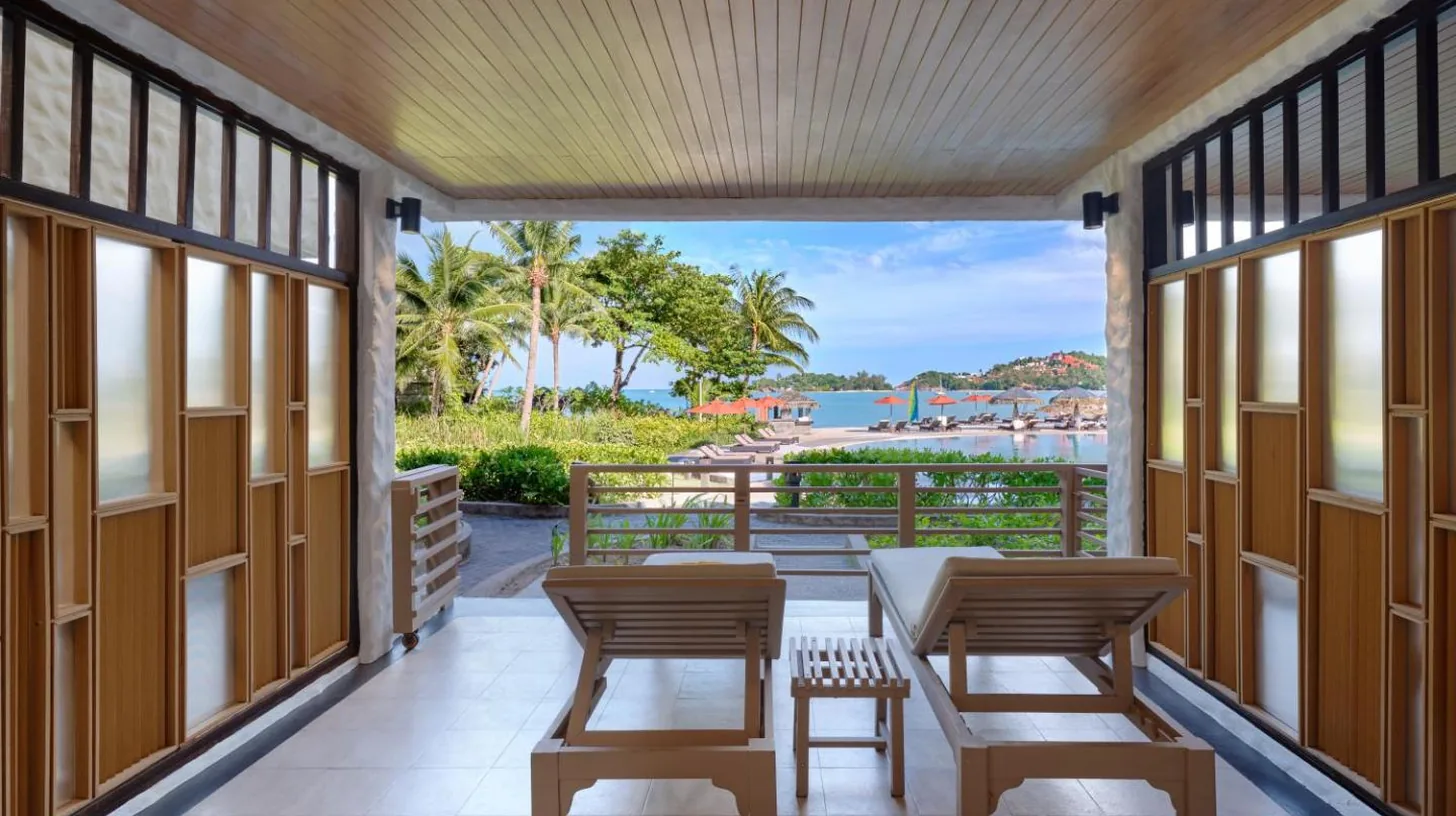 a porch with tables and chairs and a view of the water at Garrya Tongsai Bay Samui in Choeng Mon Beach