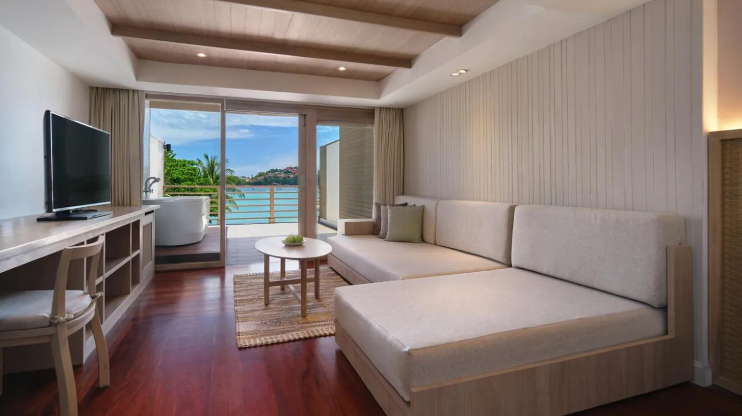a living room with a couch and a television at Garrya Tongsai Bay Samui in Choeng Mon Beach