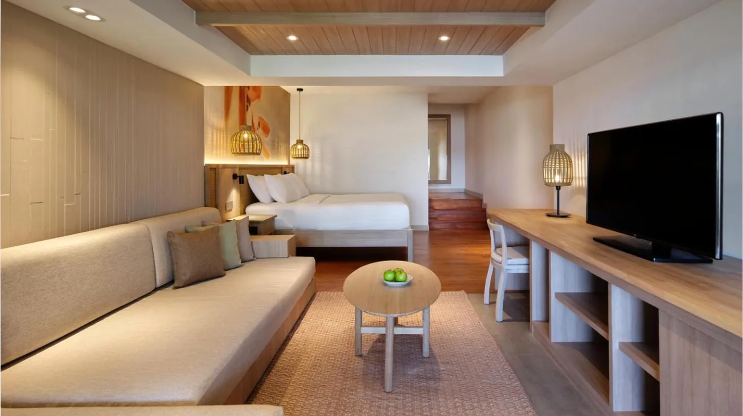 a hotel room with a couch and a tv and a bed at Garrya Tongsai Bay Samui in Choeng Mon Beach