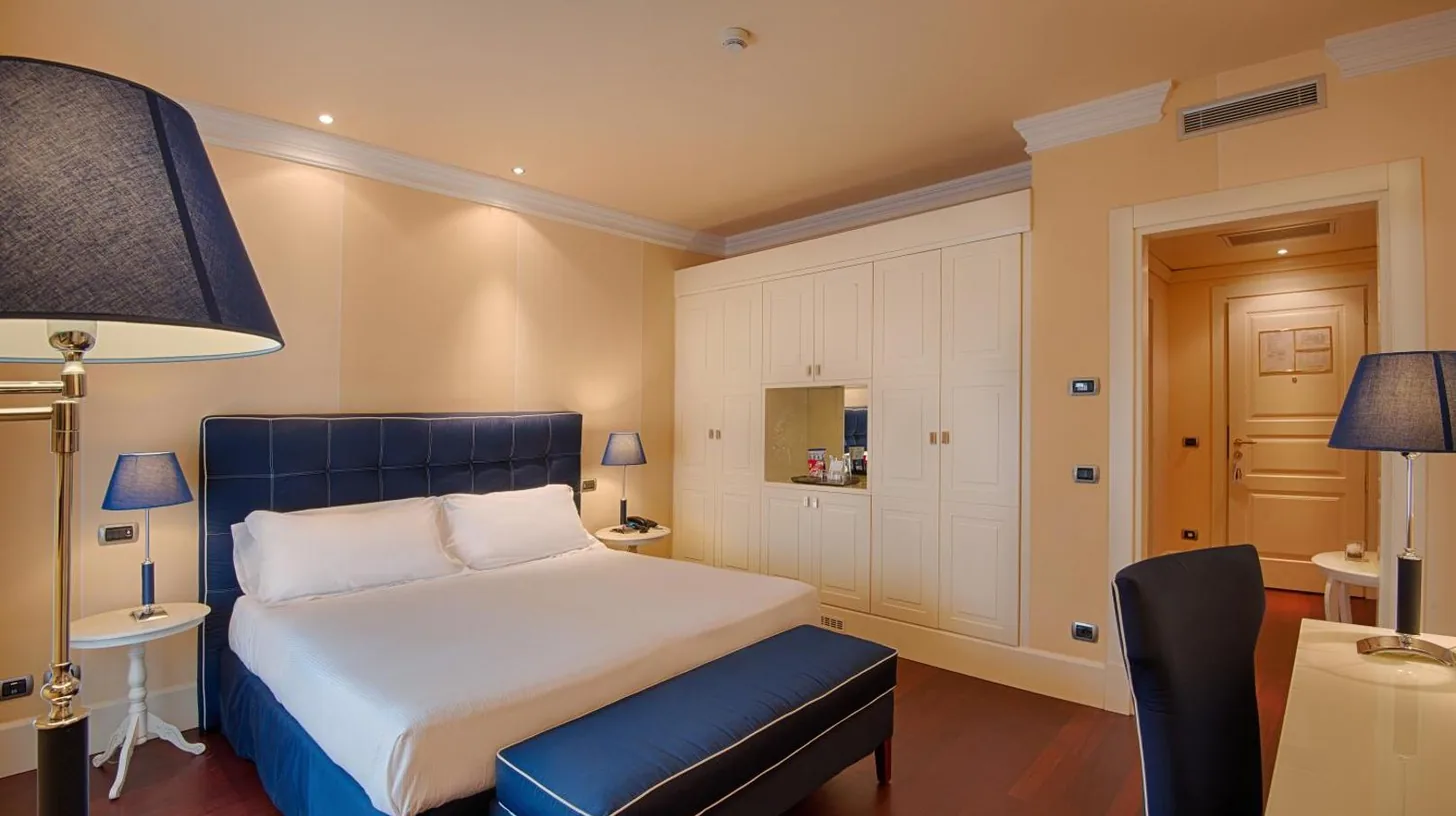 a hotel room with a bed and a desk and chairs at GH Palazzo Suite & SPA in Livorno