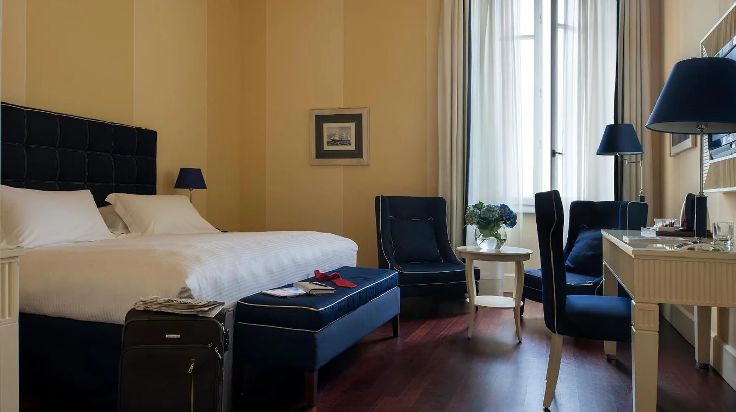 a hotel room with a bed and a table with flowers at GH Palazzo Suite & SPA in Livorno