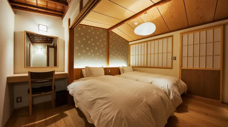 a bedroom with two beds and a desk and a table at Gion Shirakawa no Yado in Kyoto