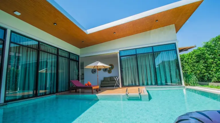 a swimming pool in a house with glass walls at Good Night Pool Villa Phuket in Phuket Town