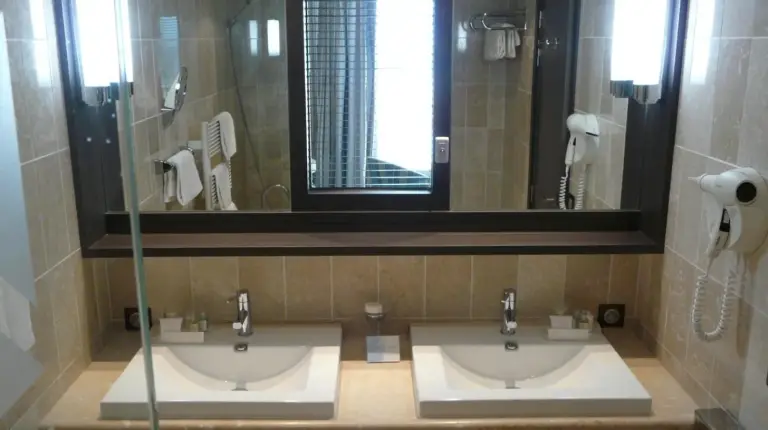 a bathroom with two sinks and a mirror and a shower at Grand Hôtel Des Thermes in Saint Malo