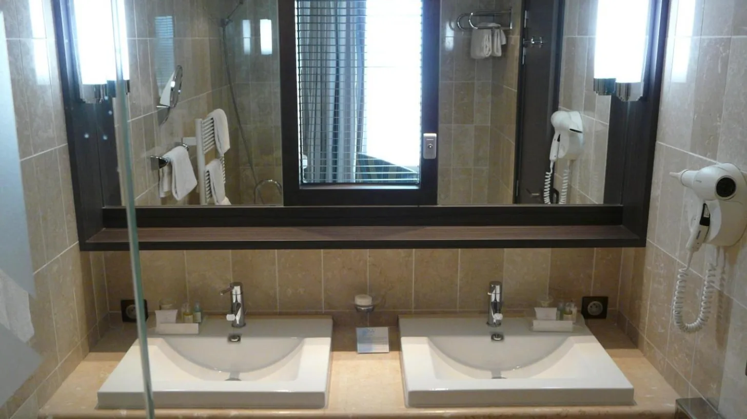 a bathroom with two sinks and a mirror and a shower at Grand Hôtel Des Thermes in Saint Malo