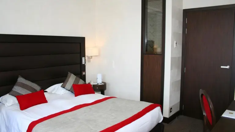 a hotel room with a large bed with red pillows at Grand Hôtel Des Thermes in Saint Malo