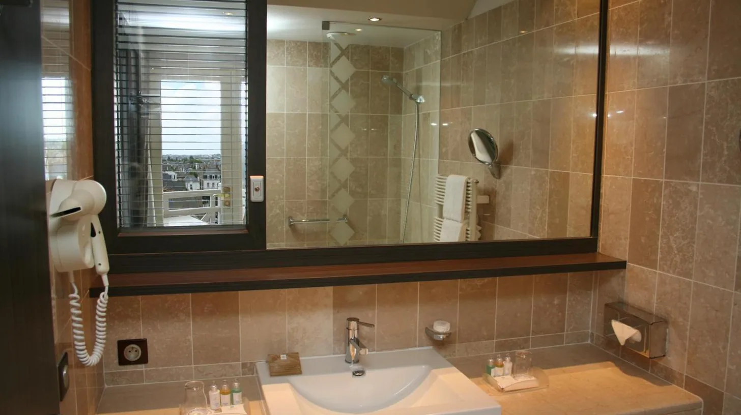 a bathroom with a sink and a mirror and a phone at Grand Hôtel Des Thermes in Saint Malo