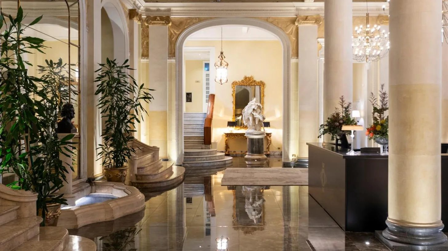 un hall avec colonnes et plantes dans un bÃ¢timent du Grand Hotel Et Des Palmes Ã  Palerme