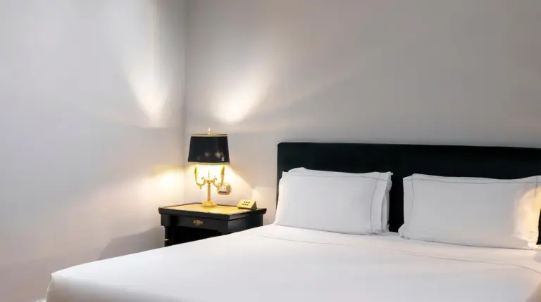 ein weiÃes Bett mit schwarzem Kopfteil und einer Lampe im Grand Hotel Et Des Palmes in Palermo