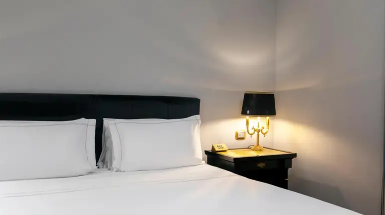 un lit avec oreillers blancs et lampe sur une table au Grand Hotel Et Des Palmes Ã  Palerme