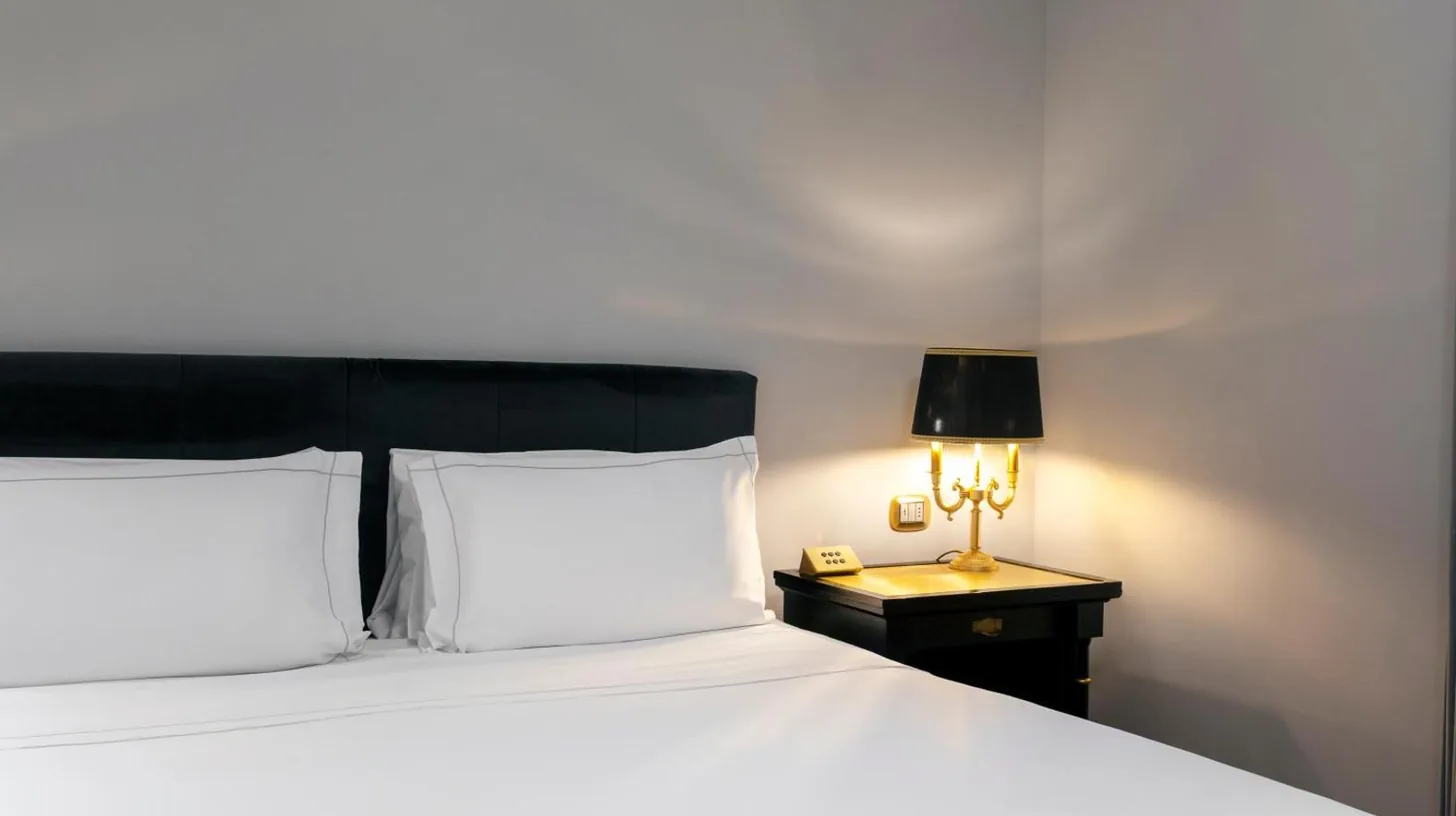 un lit avec oreillers blancs et lampe sur une table au Grand Hotel Et Des Palmes Ã  Palerme
