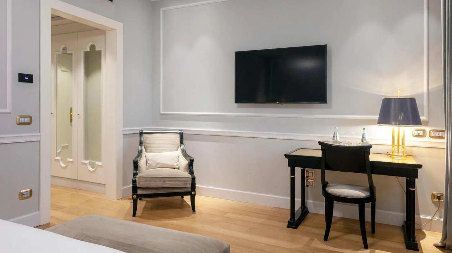 une chambre avec bureau, chaise et tÃ©lÃ©vision au Grand Hotel Et Des Palmes Ã  Palerme