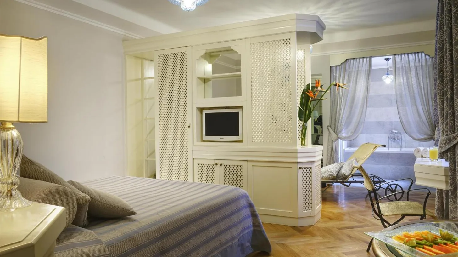 a hotel room with a bed and a flat screen tv at Grand Hotel Savoia Genova