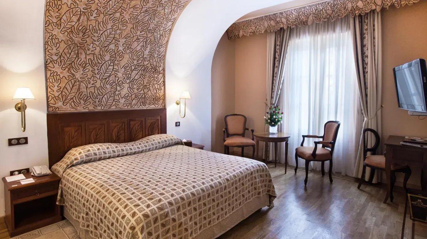 a bedroom with a bed and a table and chairs at Grand Hotel Villa de France in Tangier